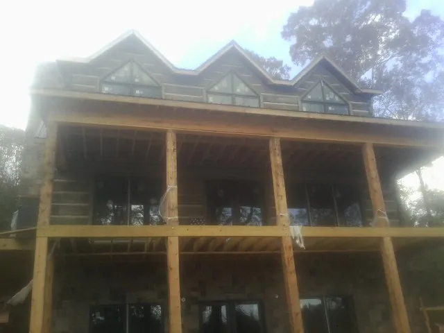 Dormers and porch framing on a large log home under construction — Roof Coating work by our crew in Buckeystown