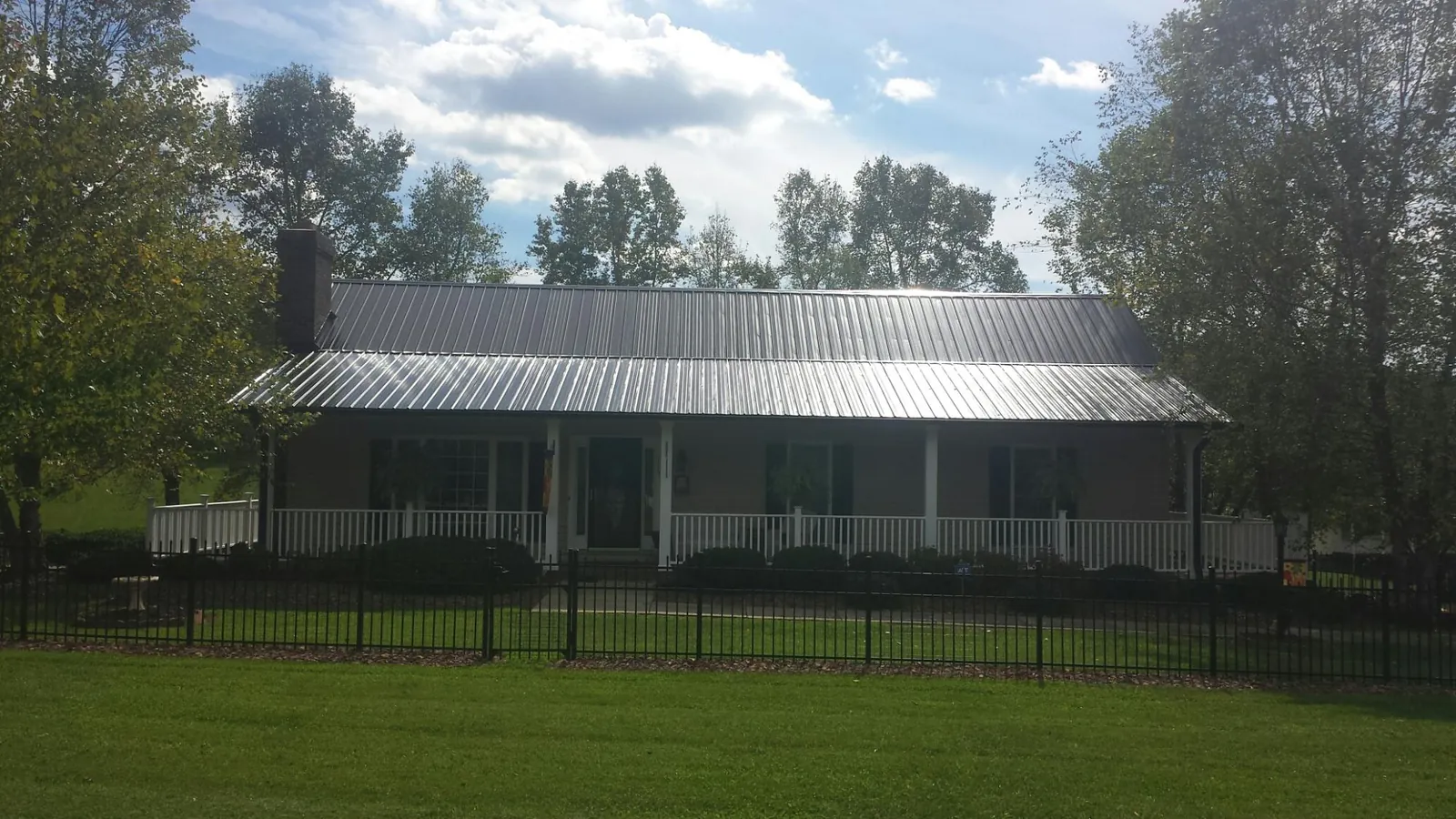 Gray metal roof on a brick ranch with a full width front porch — Gutter Guard Installation work by our crew in Buckeystown