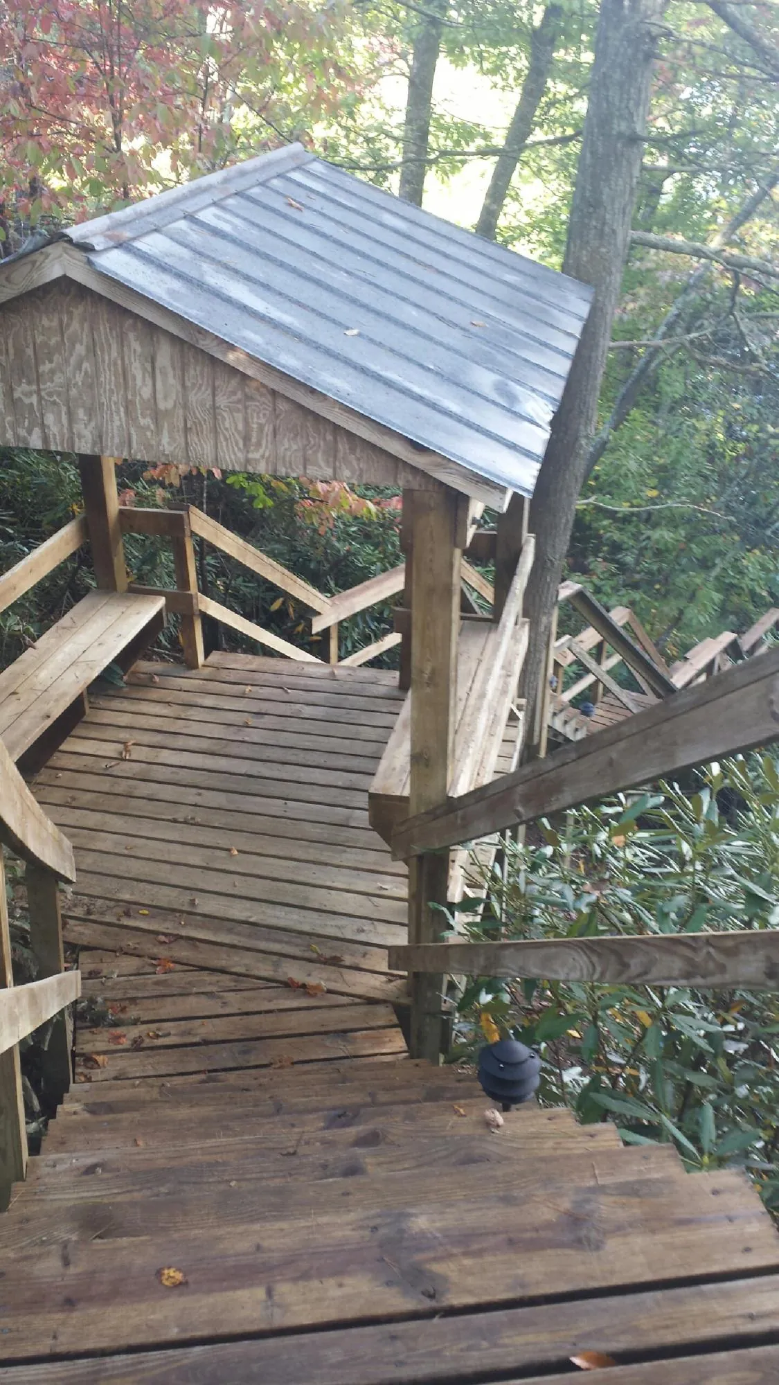Metal roofed shelter over wooden steps on a wooded walkway — Skylight Repair & Installation work by our crew in Buckeystown